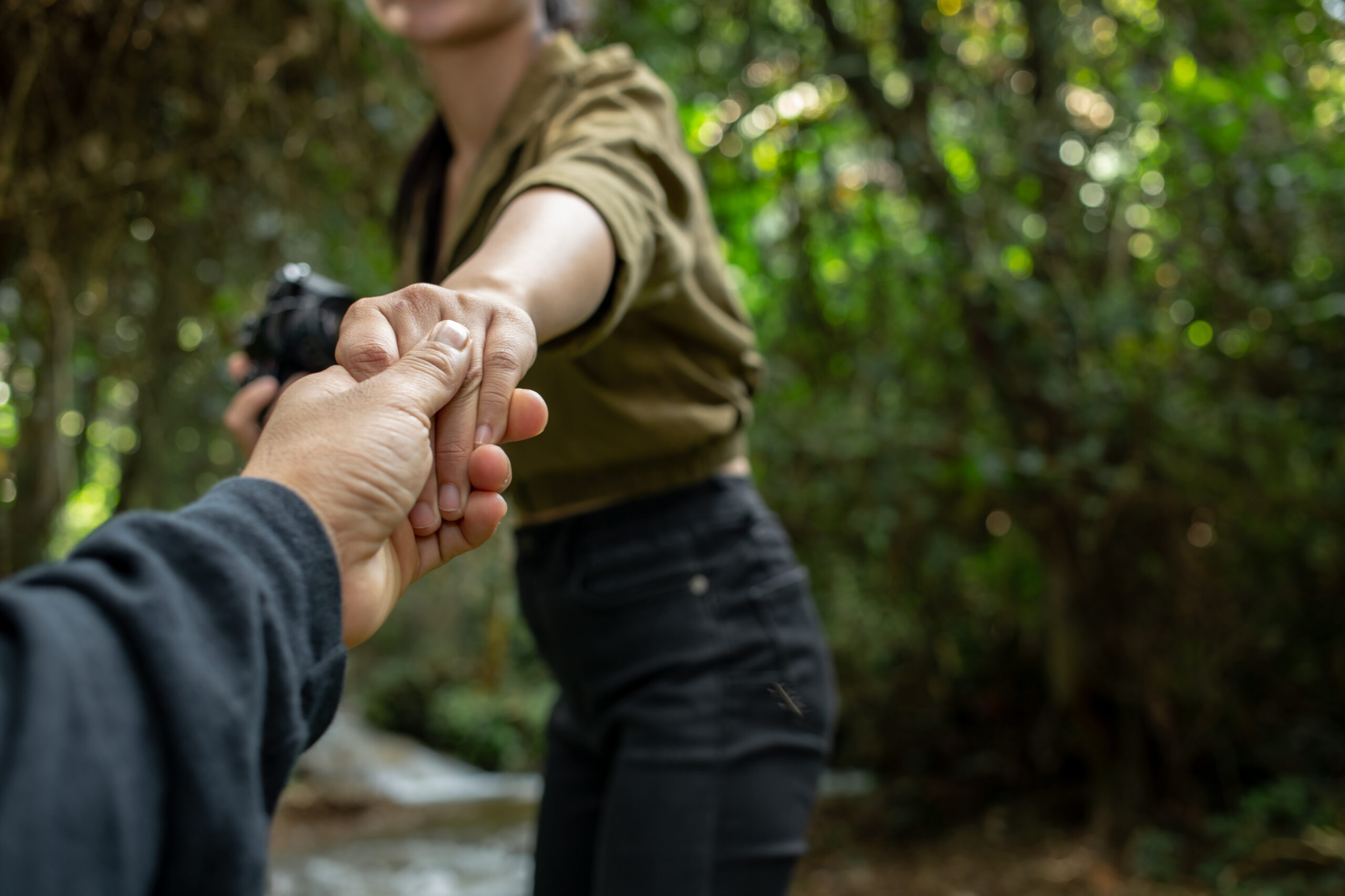 young travelers are holding hands together, walking happily in the waterfall.
